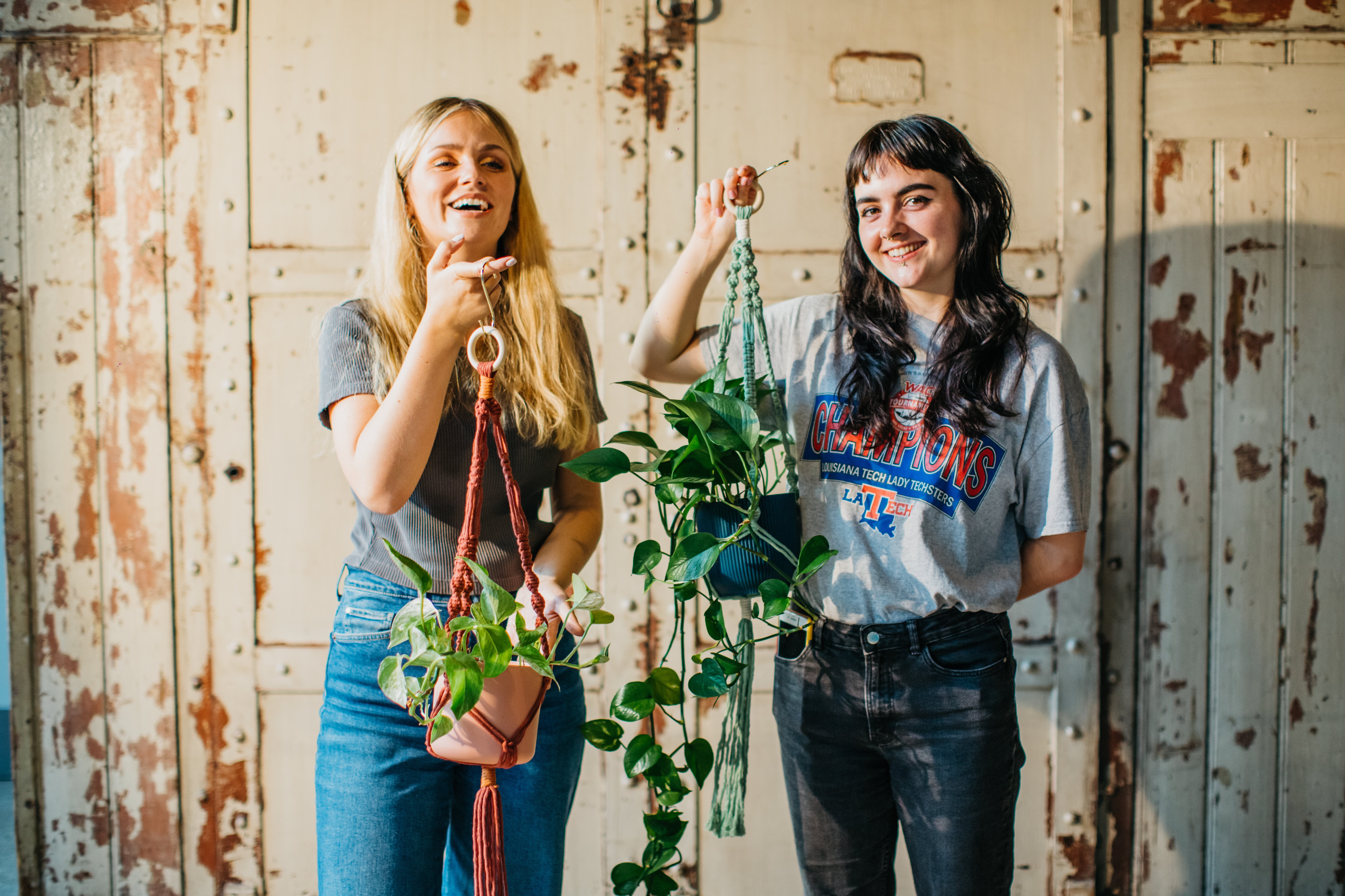 Two young women holding up handmade macrame pot holders